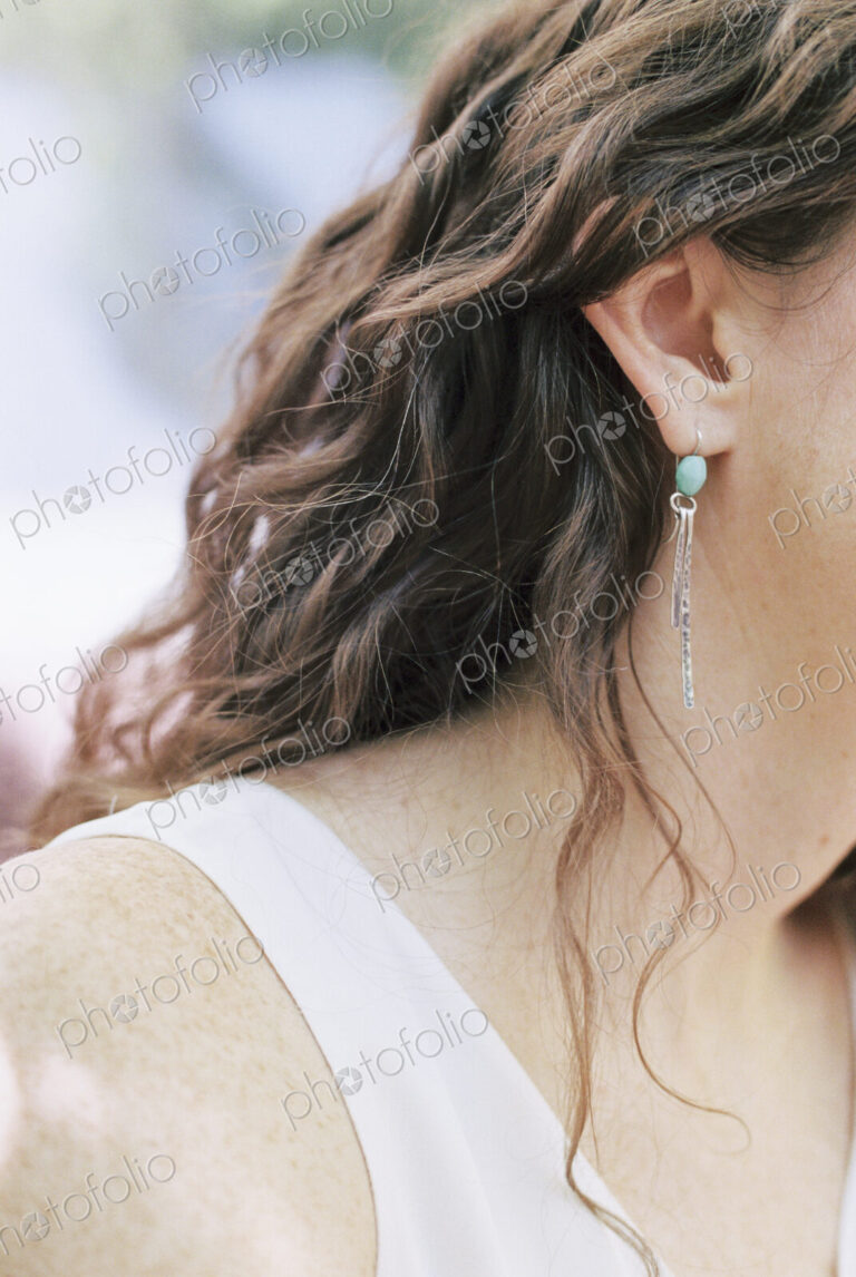 Close up of a woman wearing a silver and turquoise earring.