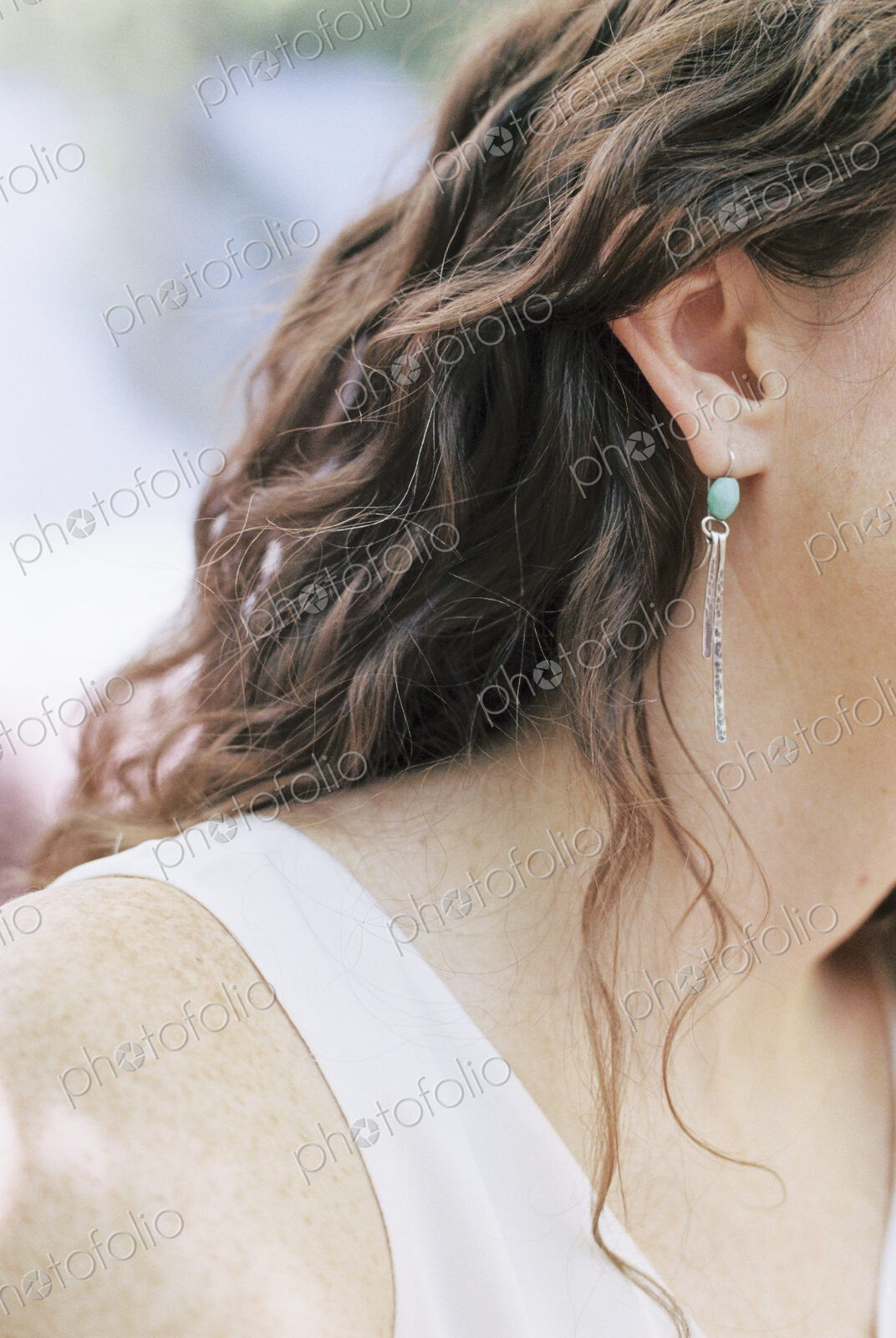 Close up of a woman wearing a silver and turquoise earring.
