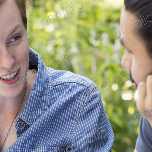 Close up of a young man and woman sitting side by side, smiling and talking. Close up of a young man and woman sitting side by side, smiling and talking.