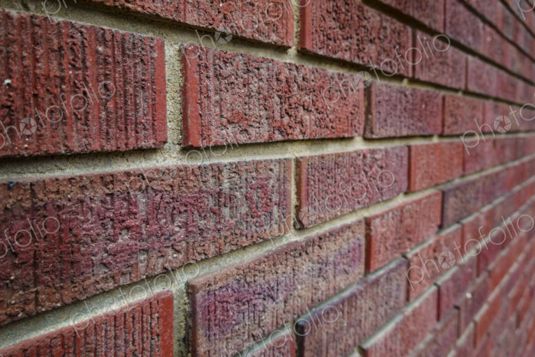 Close-up of an old clay red brick wall, laid in a running bond pattern with mortar.