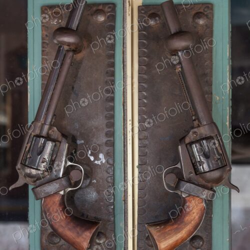 Close-up of antique revolvers repurposed as decorative door handles. Close-up of antique revolvers repurposed as decorative door handles.