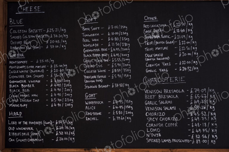 Close up of blackboard with handwritten list of cheese and charcuterie products in a…