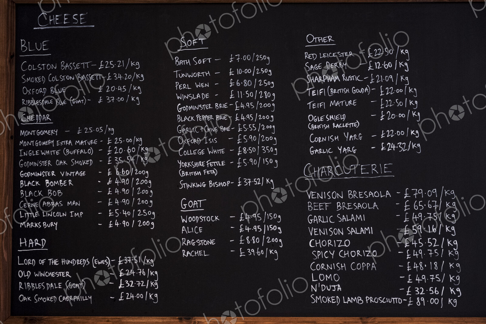 Close up of blackboard with handwritten list of cheese and charcuterie products in a…