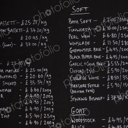 Close up of blackboard with handwritten list of cheese products in a delicatessen.