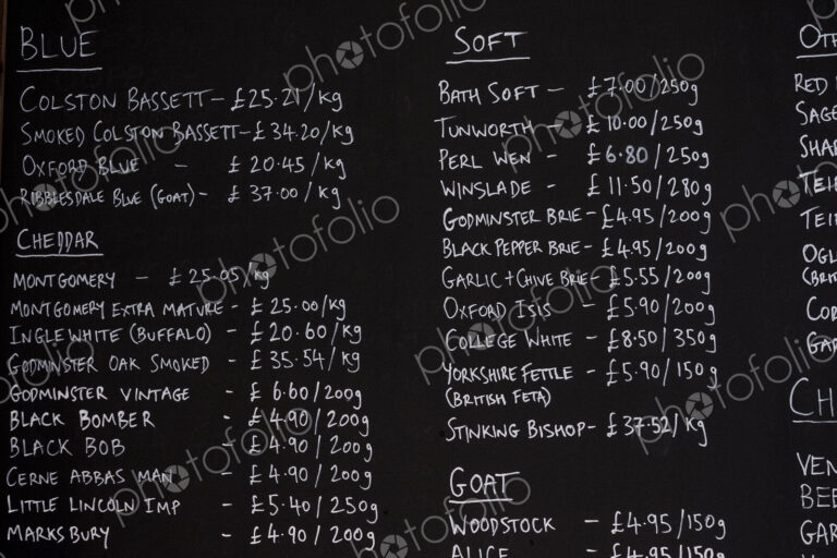 Close up of blackboard with handwritten list of cheese products in a delicatessen.