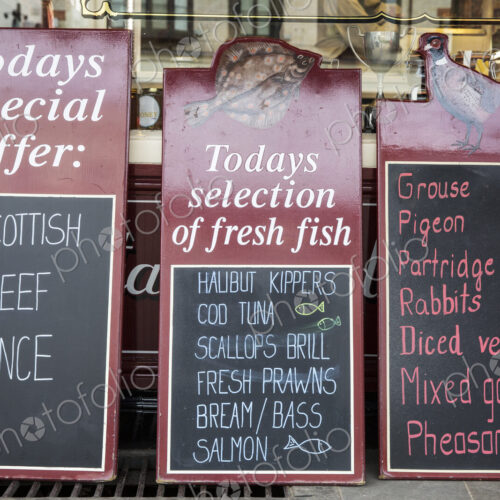 Close up of blackboards on the pavement outside a butcher shop, advertising beef,…