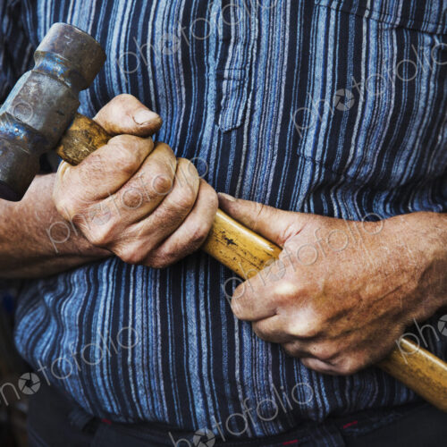 Close up of blacksmith's hands gripping a large hammer. Close up of blacksmith's hands gripping a large hammer.