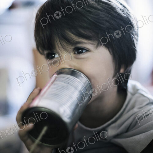 Close up of boy playing with tin can telephone Close up of boy playing with tin can telephone