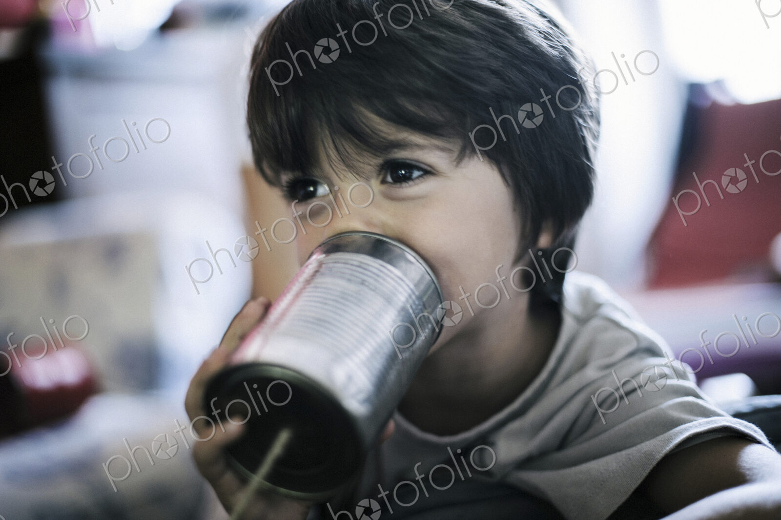 Close up of boy playing with tin can telephone