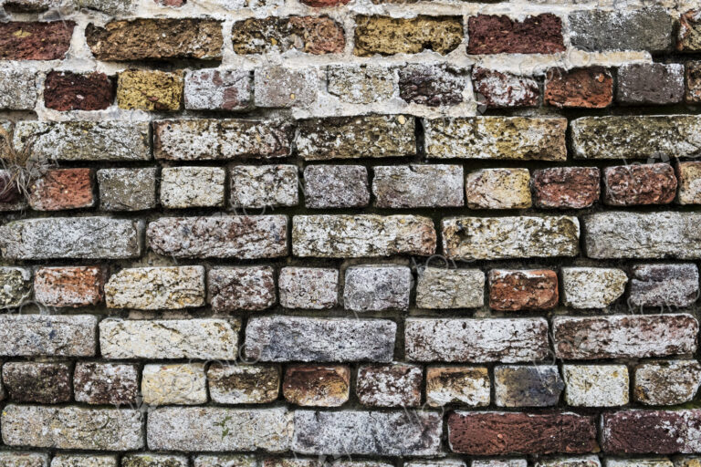 Close up of brick wall with bricks in a variety of colours and textures.
