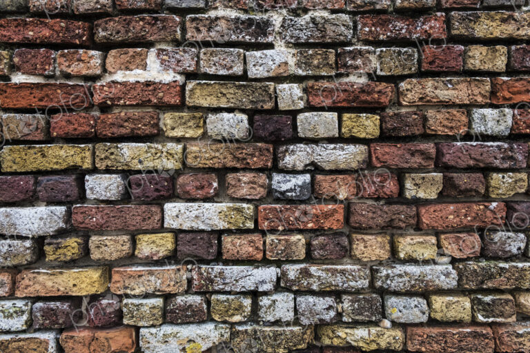 Close up of brick wall with bricks in a variety of colours and textures.