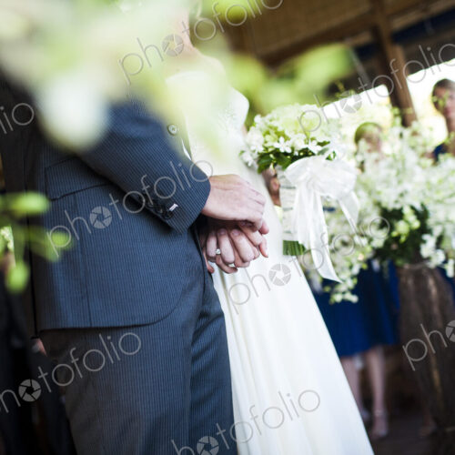 Close up of bride and groom holding hands at a wedding ceremony.