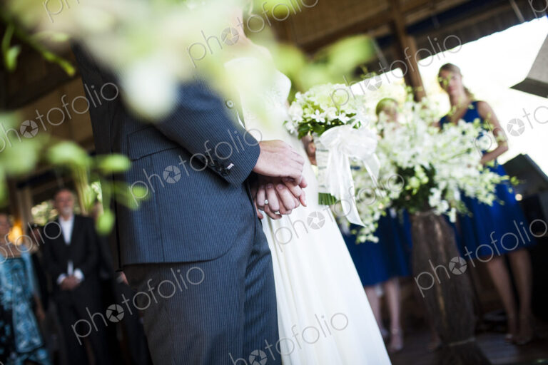 Close up of bride and groom holding hands at a wedding ceremony.