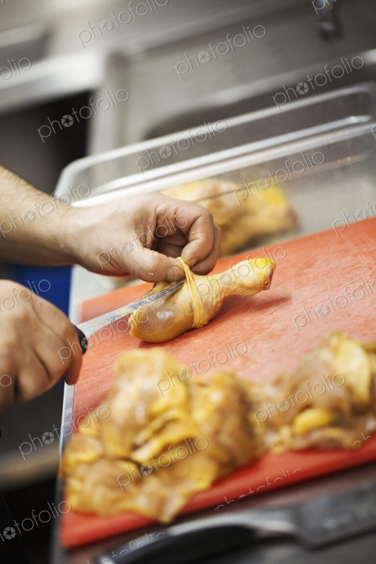 Close up of chef preparing a chicken drumstick in the kitchen at a hotel.