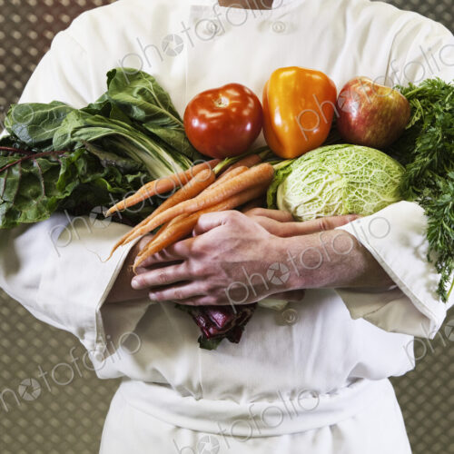 Close-up of chef with his arms full of freshly picked vegetables. Close-up of chef with his arms full of freshly picked vegetables.