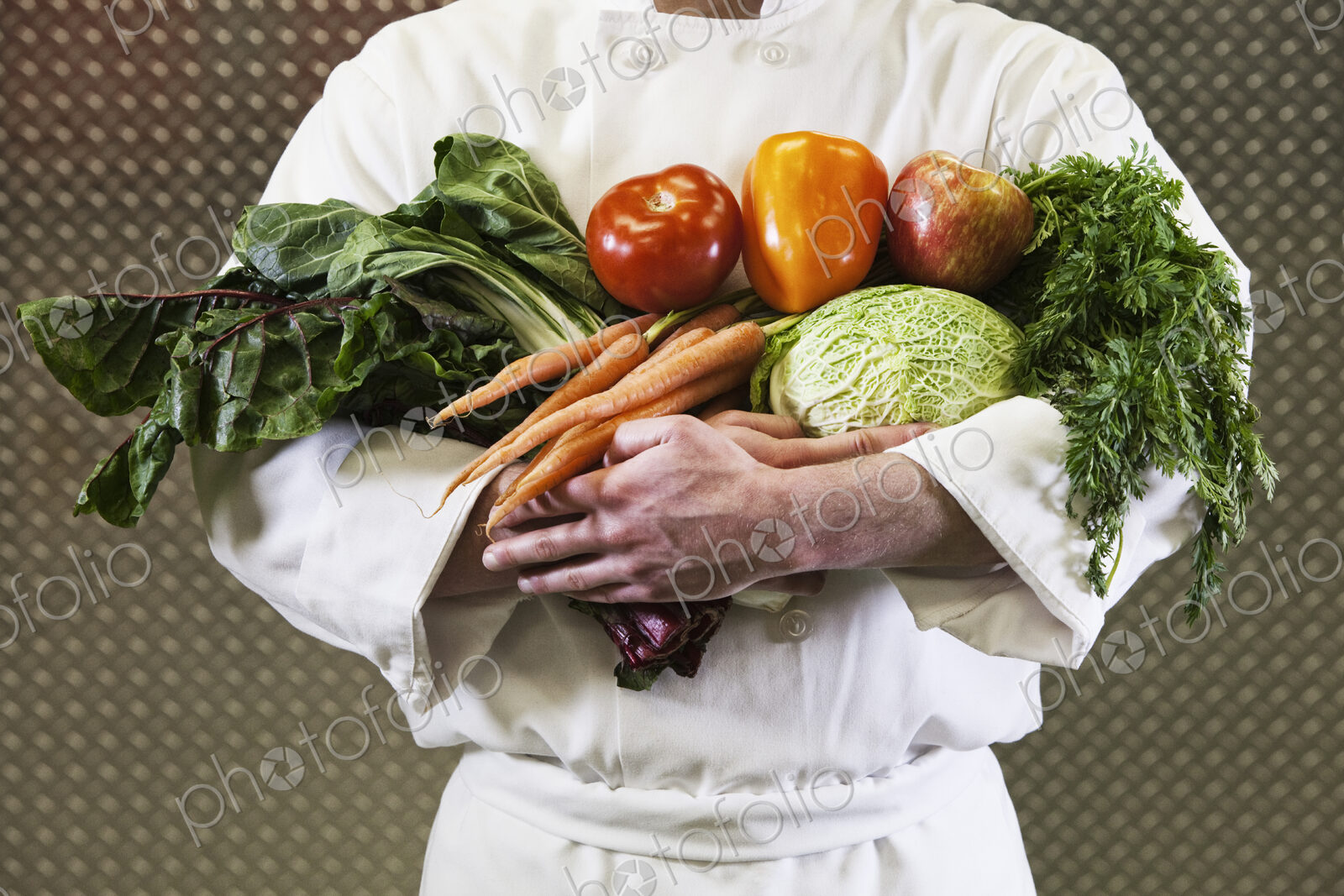 Close-up of chef with his arms full of freshly picked vegetables.