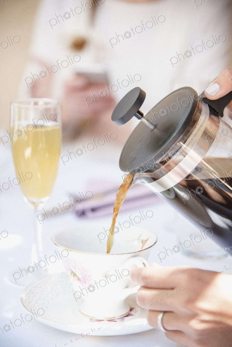 Close up of coffee being poured from a French Coffee Press into a cup, a glass of…