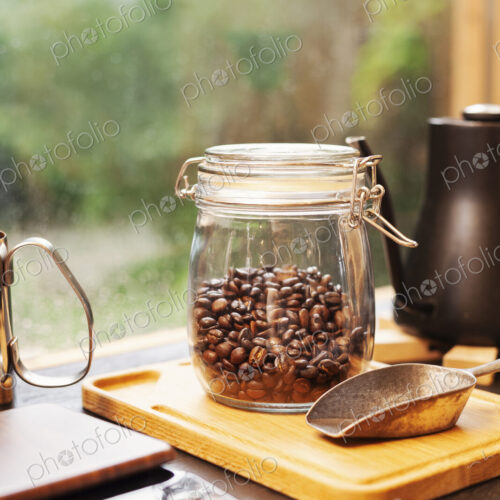 Close up of coffee pot, glass jar with coffee beans and metal coffee shovel on wooden… Close up of coffee pot, glass jar with coffee beans and metal coffee shovel on wooden…