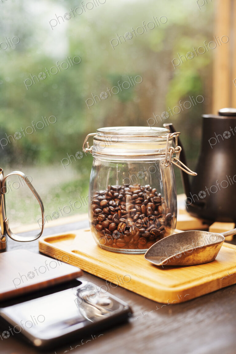 Close up of coffee pot, glass jar with coffee beans and metal coffee shovel on wooden…