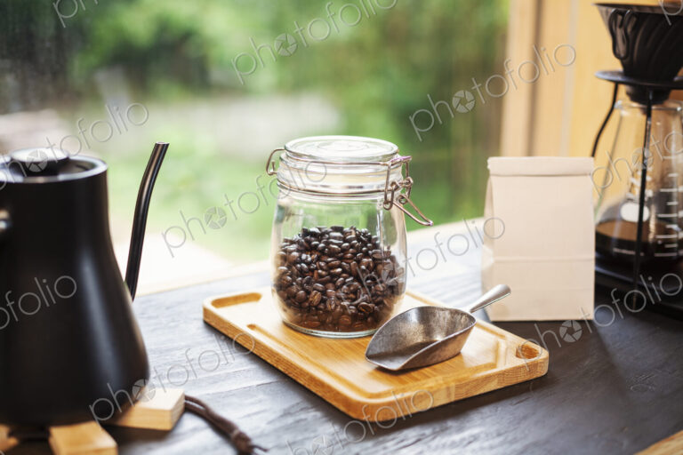 Close up of coffee pot, glass jar with coffee beans and metal coffee shovel on wooden…