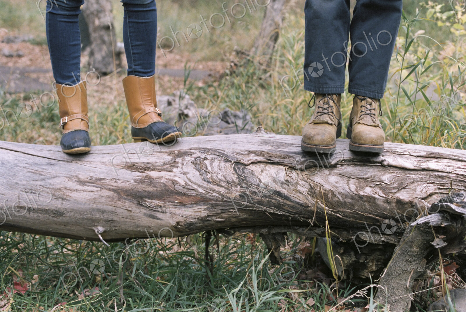 Close up of couple standing side by side on a tree trunk.