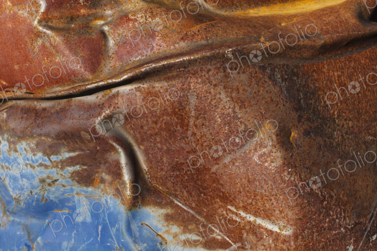 Close up of dented and rusty old blue metal oil drum.