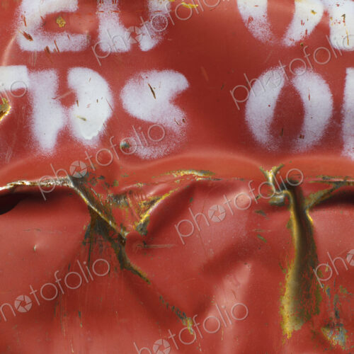 Close up of dented and rusty old red metal oil drum with white lettering. Close up of dented and rusty old red metal oil drum with white lettering.