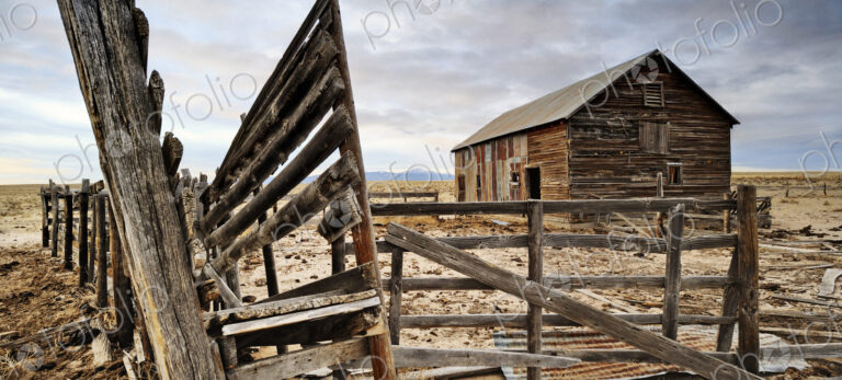Close up of dilapidated fence and barn on abandoned farm