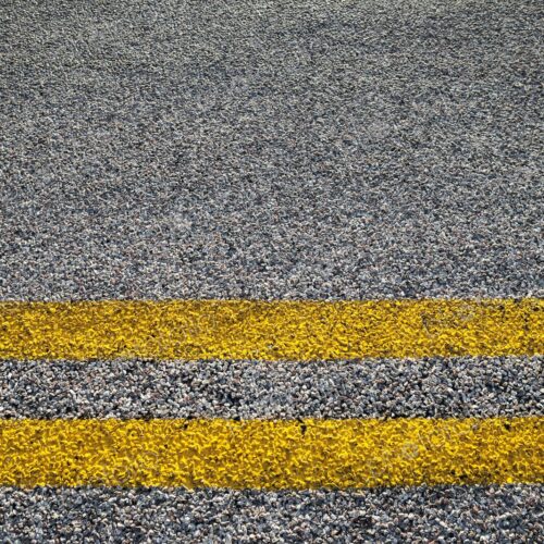 Close-up of double yellow lines painted on an asphalt road, symbolizing rules, safety,… Close-up of double yellow lines painted on an asphalt road, symbolizing rules, safety,…