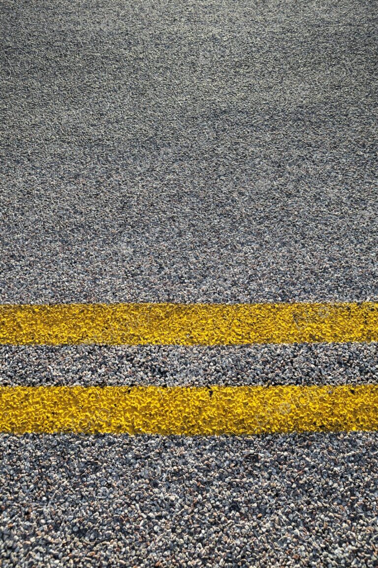 Close-up of double yellow lines painted on an asphalt road, symbolizing rules, safety,…