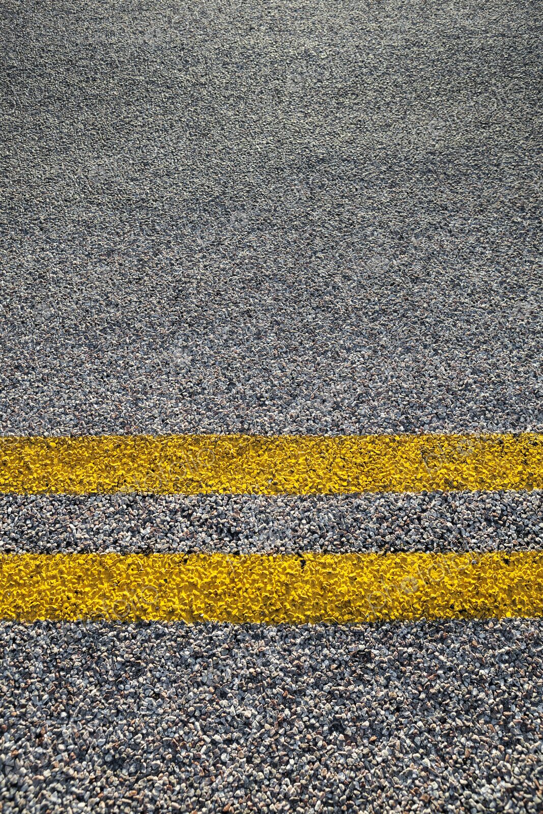 Close-up of double yellow lines painted on an asphalt road, symbolizing rules, safety,…