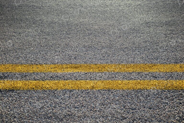 Close-up of double yellow lines painted on an asphalt road, symbolizing rules, safety,…