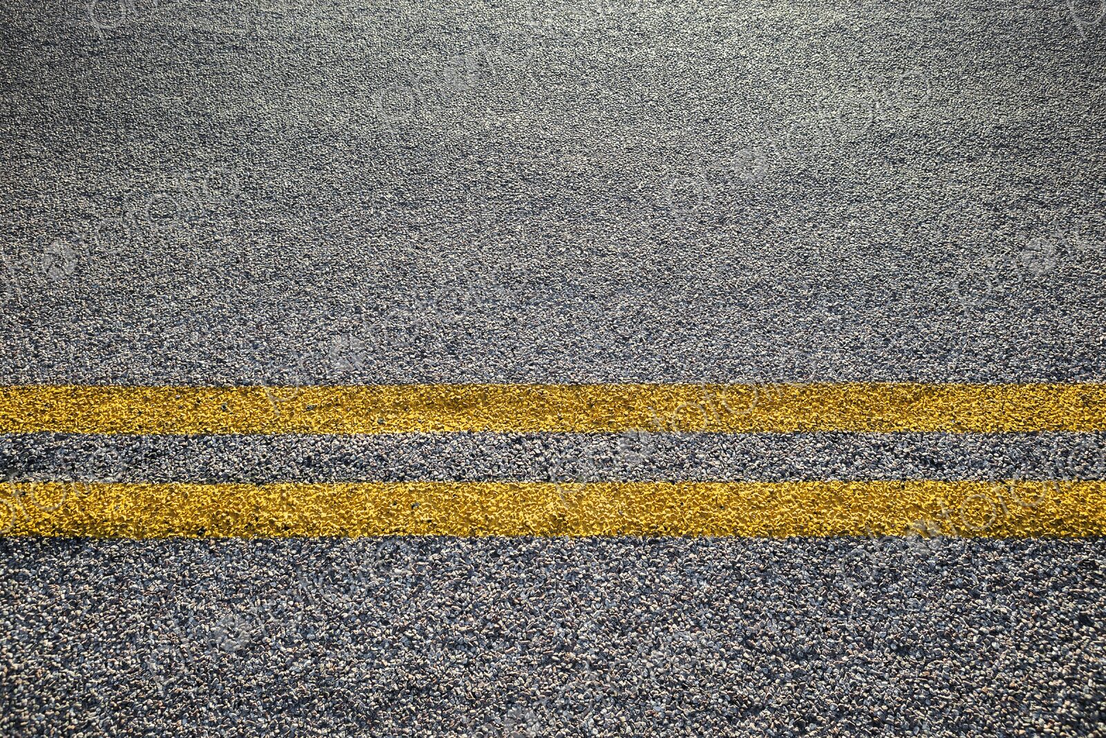 Close-up of double yellow lines painted on an asphalt road, symbolizing rules, safety,…