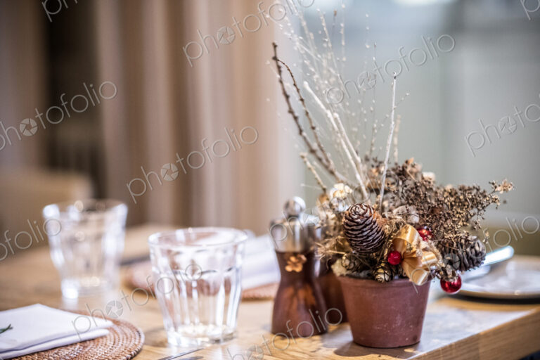 Close up of drinking glasses and Christmas decorations on wooden dining table.