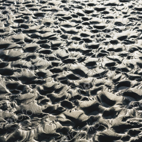Close up of erosional sand patterns on beach and intertidal zone,