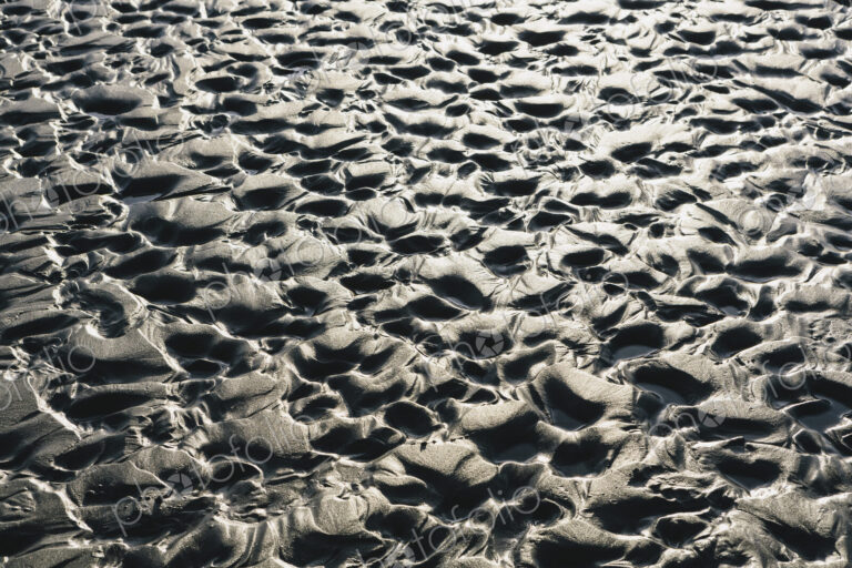 Close up of erosional sand patterns on beach and intertidal zone,