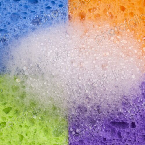 Close-up of four brightly colored household sponges arranged in a grid formation with… Close-up of four brightly colored household sponges arranged in a grid formation with…