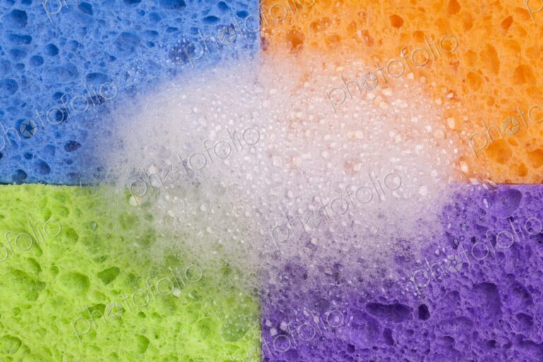 Close-up of four brightly colored household sponges arranged in a grid formation with…