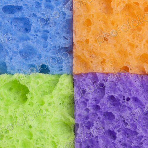 Close-up of four household sponges arranged in a square grid pattern with vivid colors…
