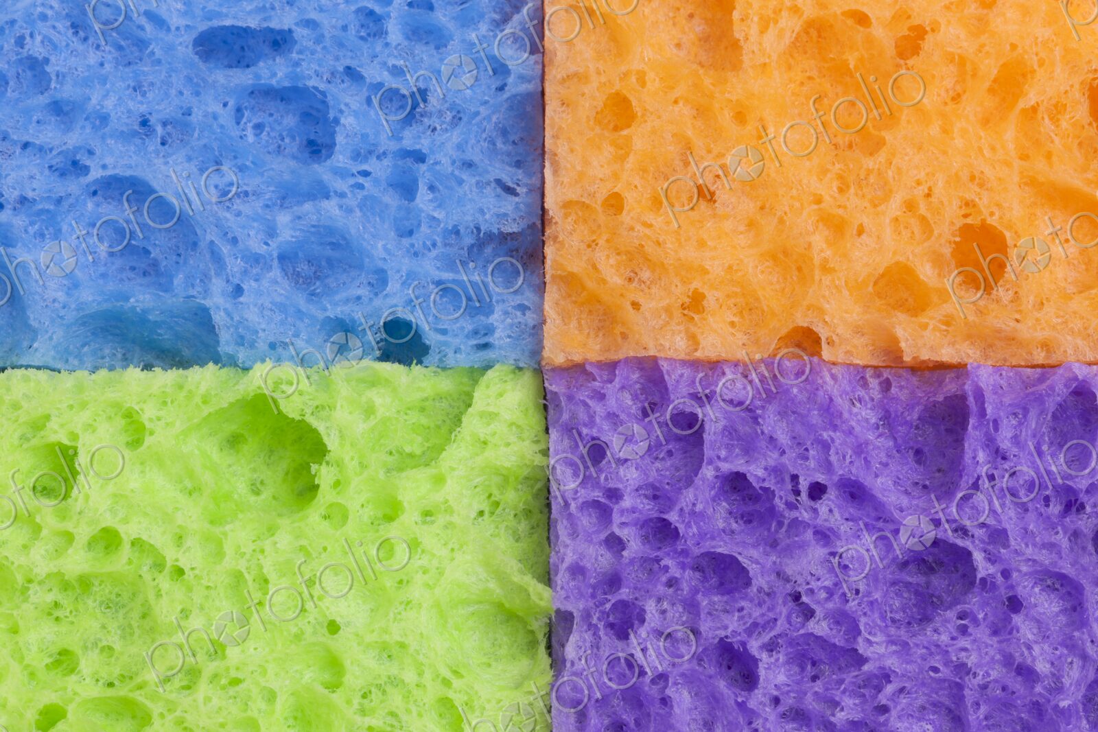 Close-up of four household sponges arranged in a square grid pattern with vivid colors…