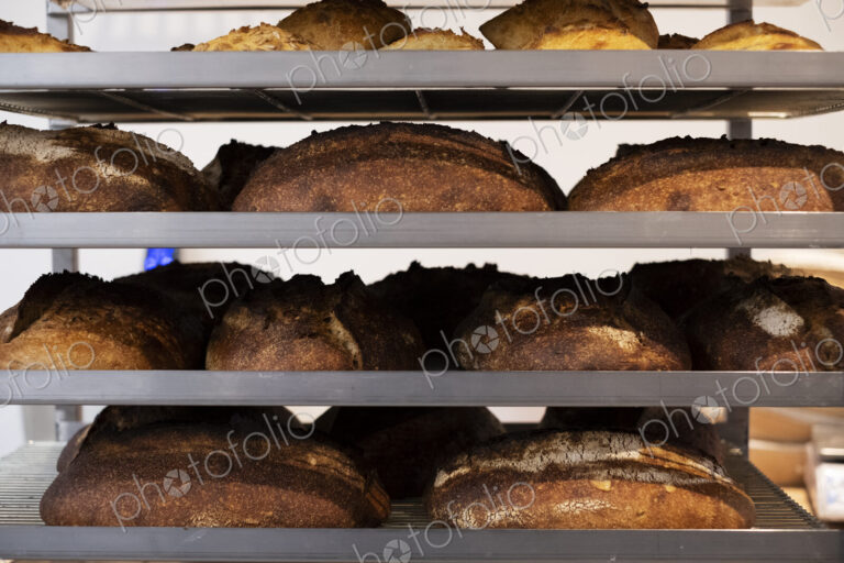 Close up of freshly baked loaves of bread on trolley shelves in an artisan bakery.