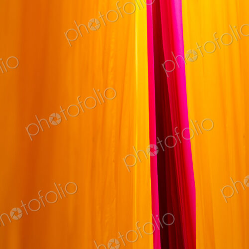 Close up of freshly dyed bright yellow and pink fabric hanging up to dry.
