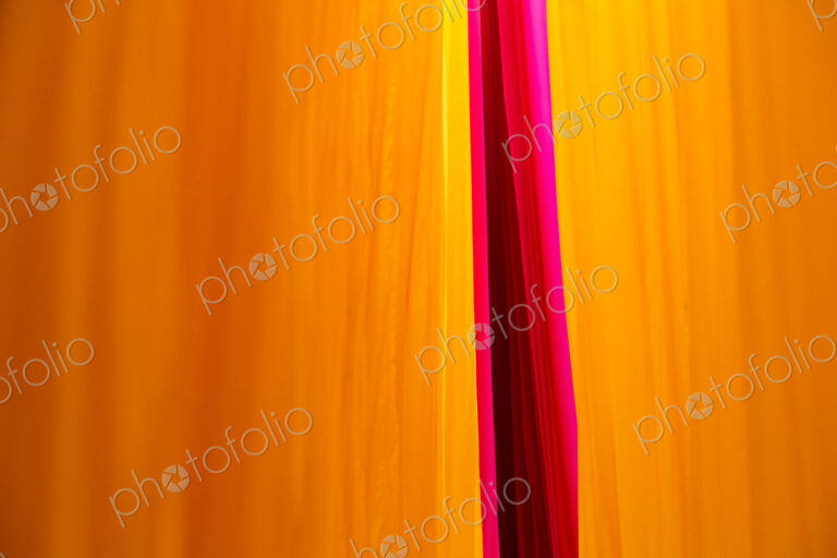 Close up of freshly dyed bright yellow and pink fabric hanging up to dry.
