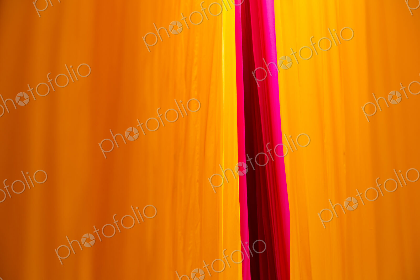 Close up of freshly dyed bright yellow and pink fabric hanging up to dry.