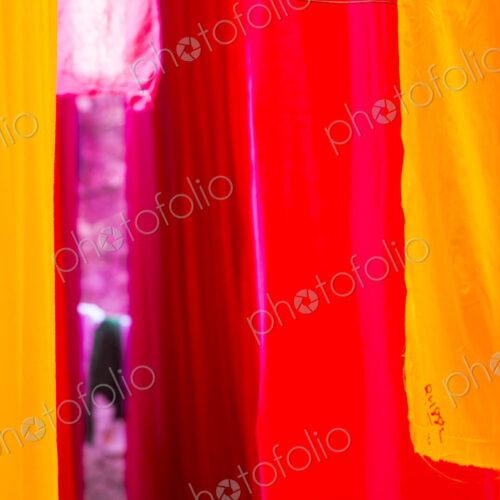 Close up of freshly dyed bright yellow and pink fabric hanging up to dry.
