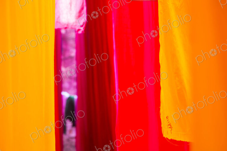 Close up of freshly dyed bright yellow and pink fabric hanging up to dry.