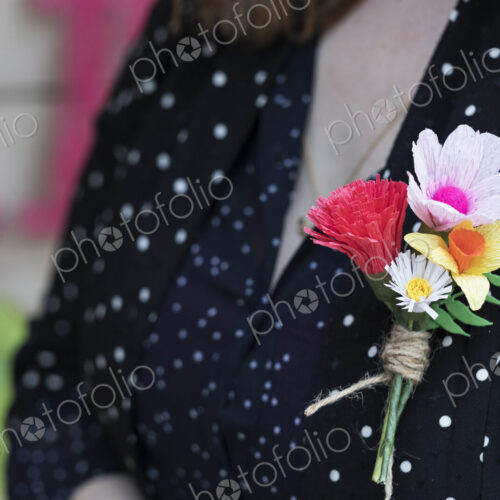 Close up of handcrafted boutonniere pinned to a women's dress.