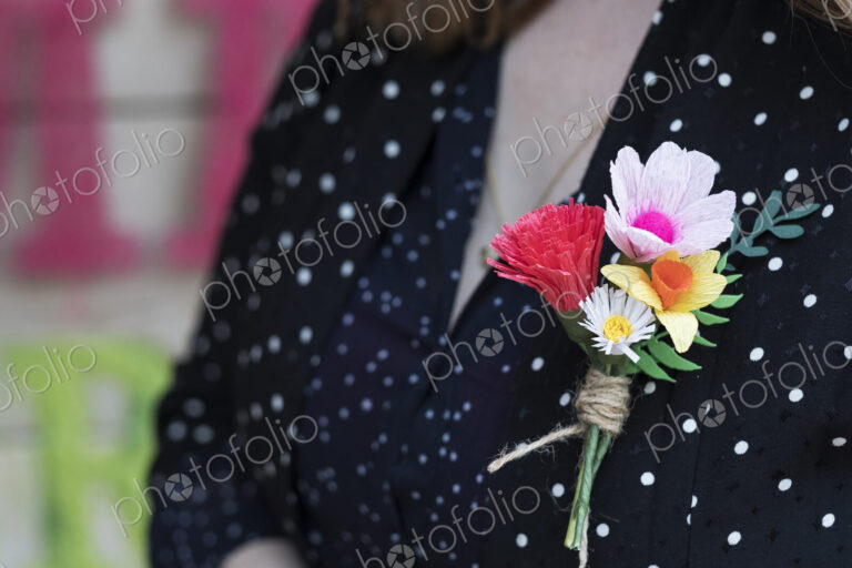 Close up of handcrafted boutonniere pinned to a women's dress.