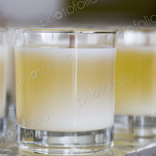 Close up of handmade white and yellow jar candles with wooden wick. Close up of handmade white and yellow jar candles with wooden wick.
