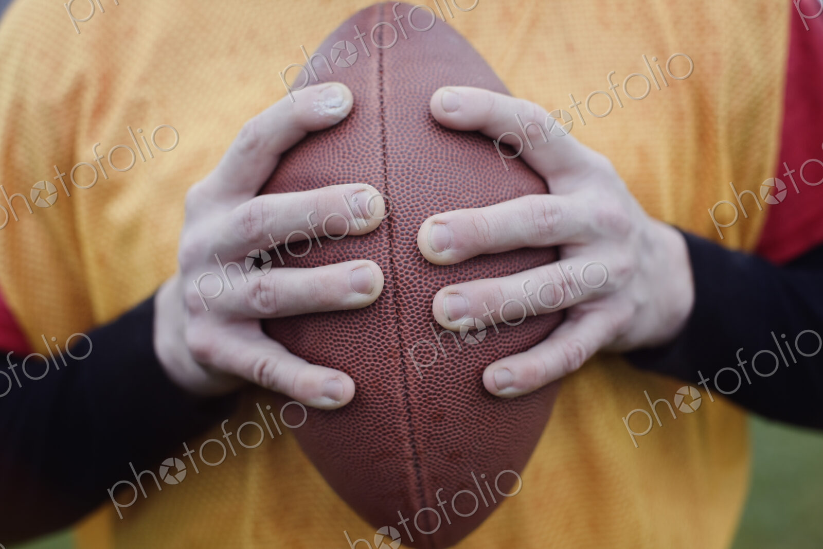 Close up of hands holding an American football.